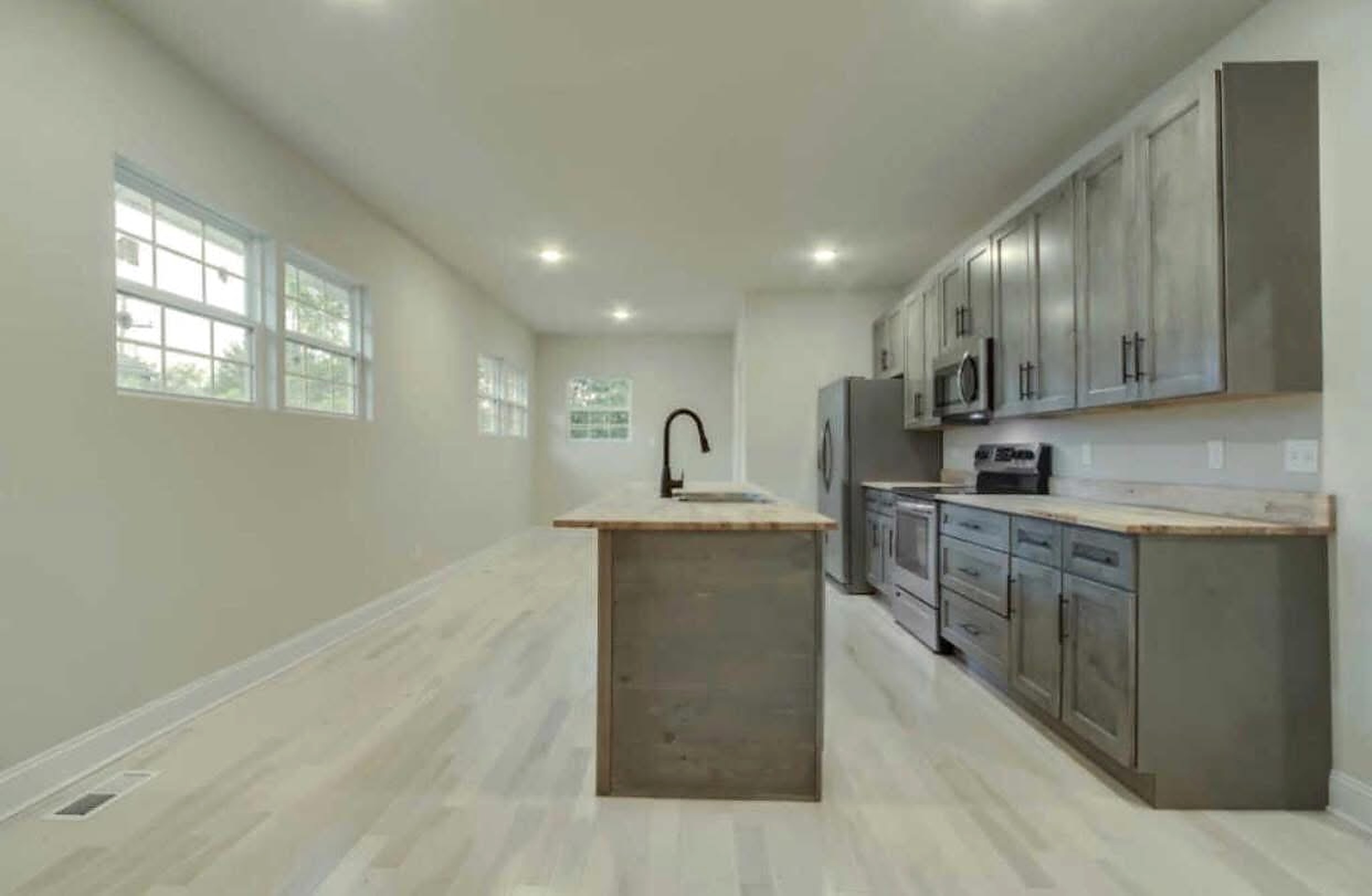 Completed bright kitchen with gray cabinets, central island, and pale flooring