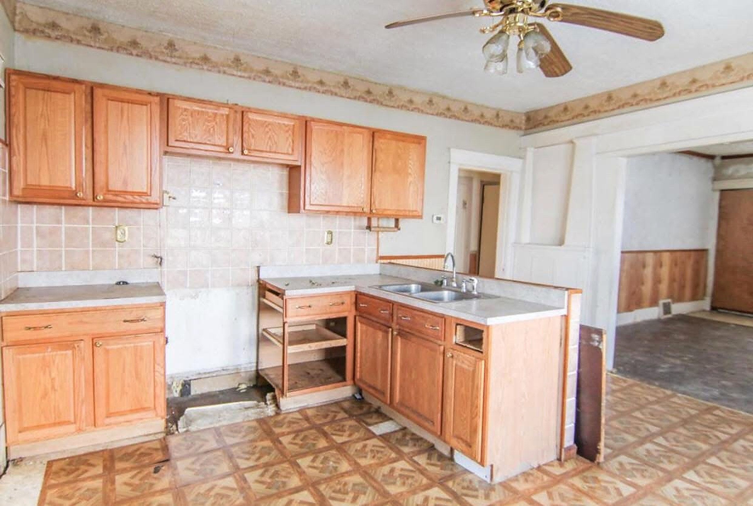 Original dated kitchen with oak cabinetry and patterned flooring before renovation
