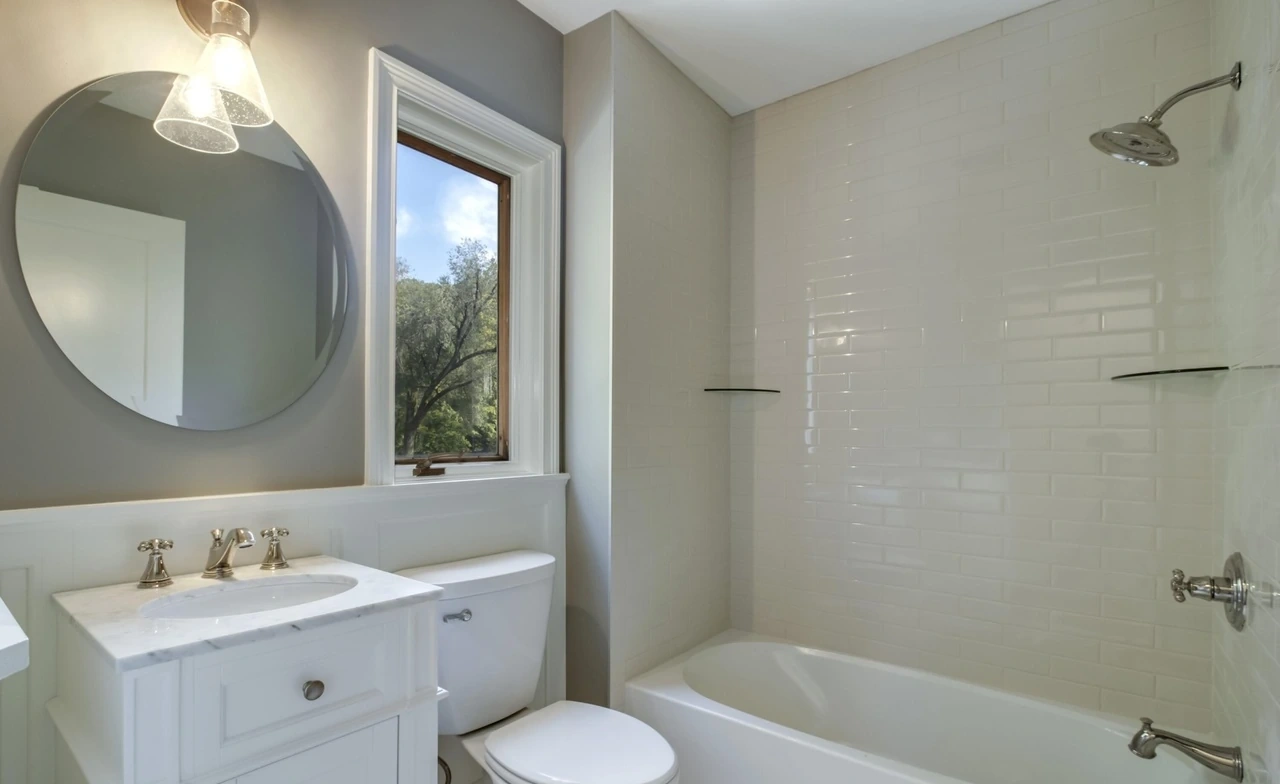 Bathroom with tiled tub surround and white vanity