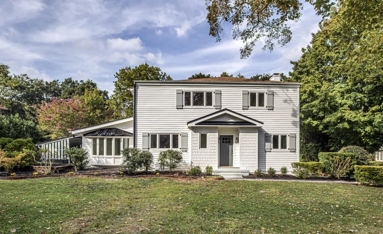 White two-story house with covered porch and lawn