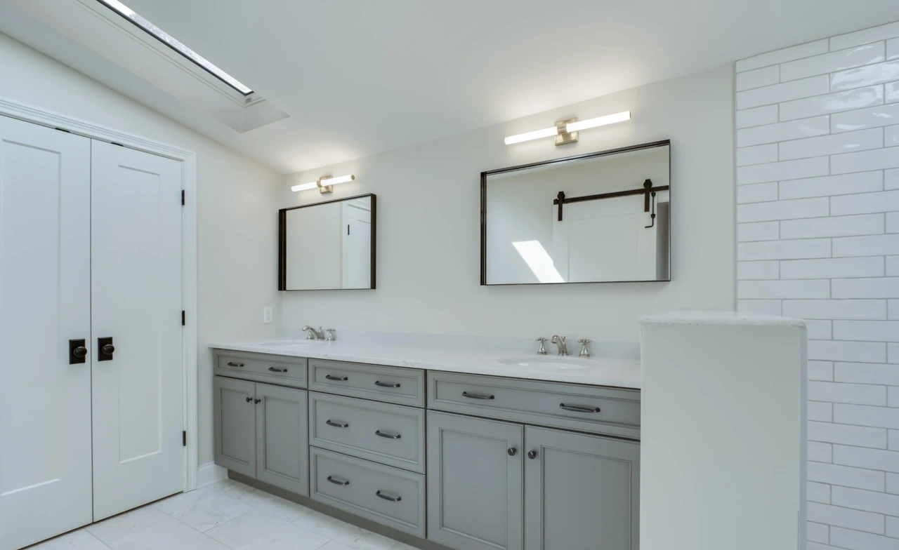 Renovated primary bathroom with double vanity, separate mirrors and tiled shower